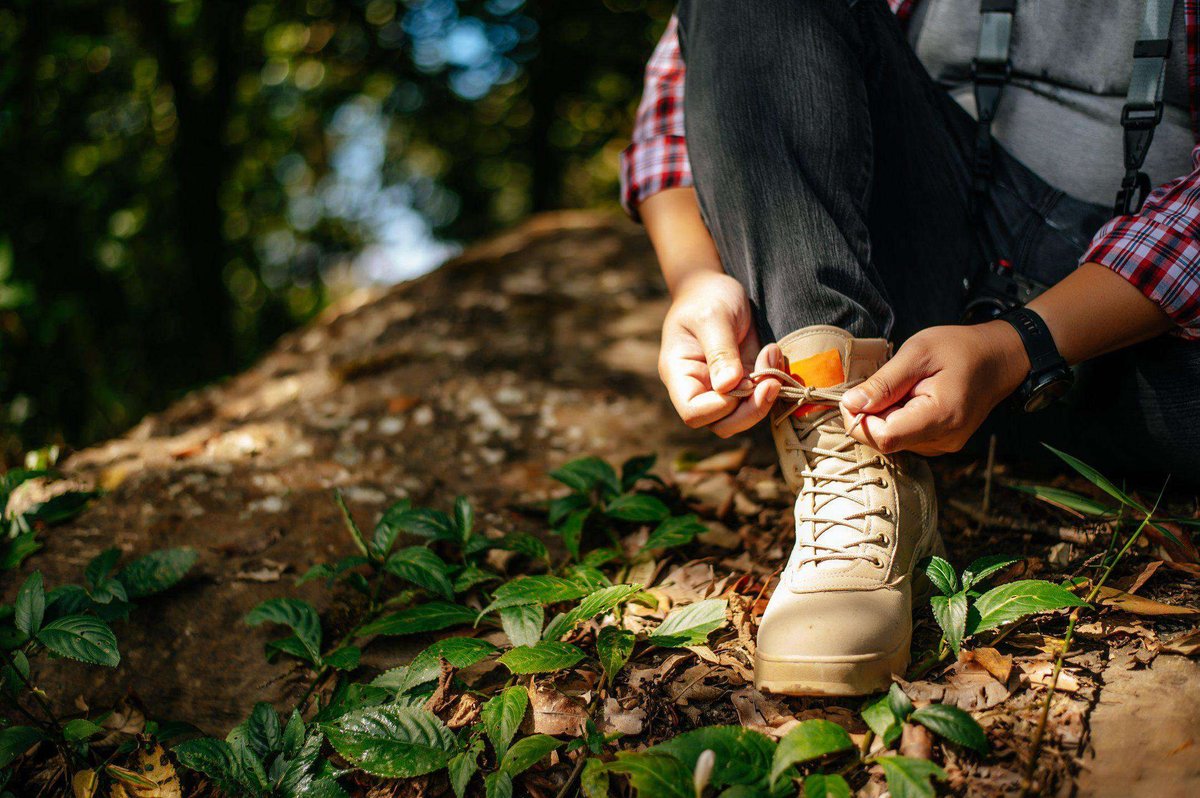 close-up-hand-young-man-sitting-tying-shoelaces-during-walking-trail-copy-space
