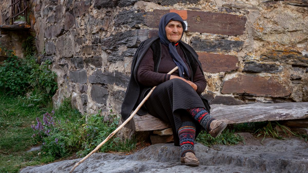 Пожилая женщина сидит перед Сванской башней