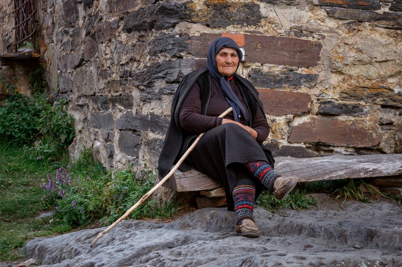 Пожилая женщина сидит перед Сванской башней