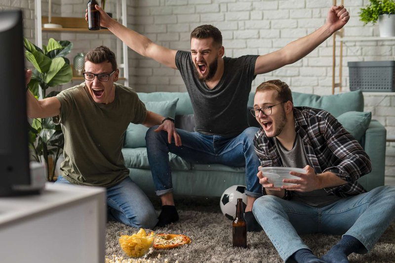 front-view-of-cheerful-male-friends-watching-sports-on-tv-together-while-having-snacks-and-beer.jpg