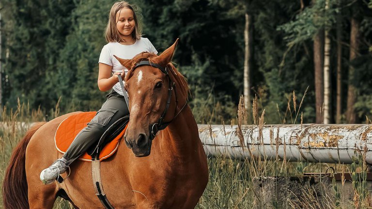 Радостная молодая девушка верхом на лошади