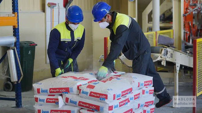 Рабочие компании строительных материалов "Knauf Gypsum Tbilisi" слаживают мешки с цементом