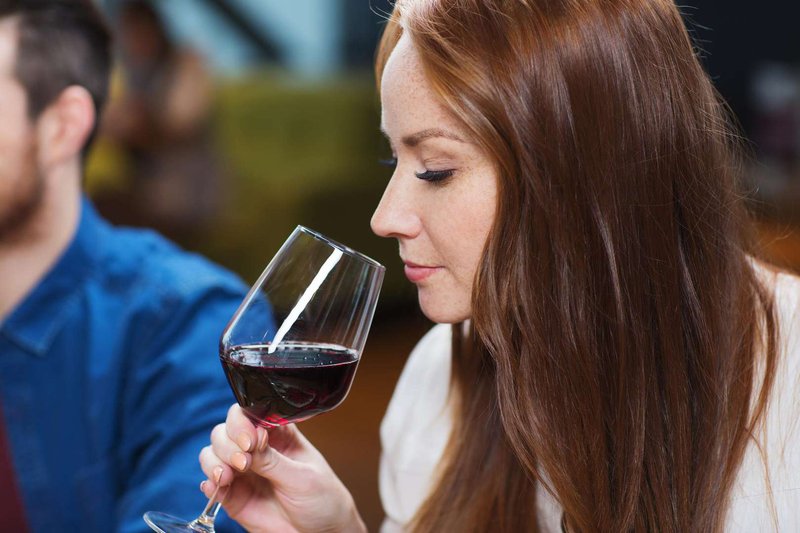 A girl is tasting red wine