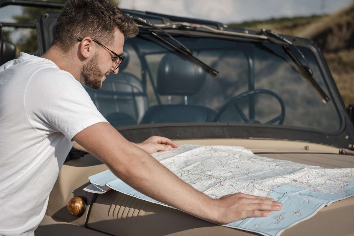 man-checking-map-while-traveling-by-car