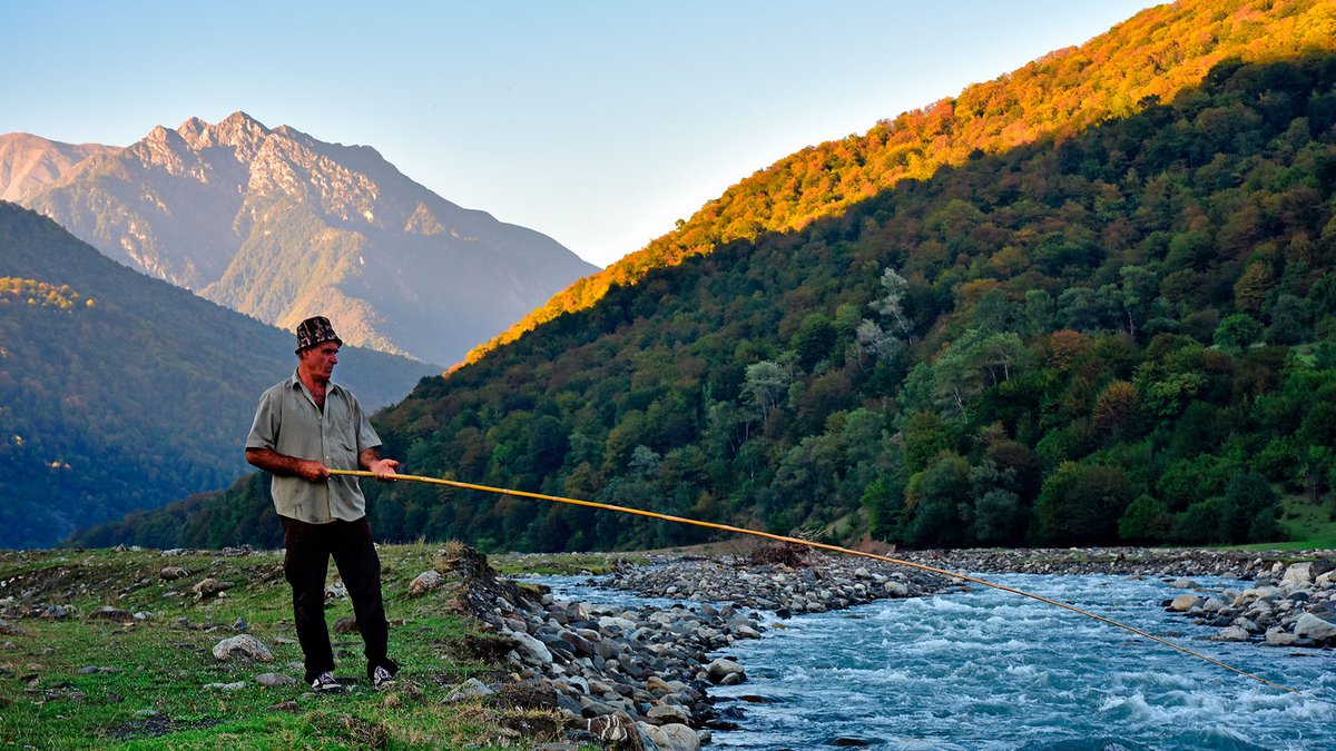 Рыбак с удочкой у горной реки Грузии
