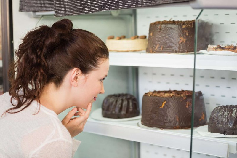 A girl chooses a cake in a pastry shop