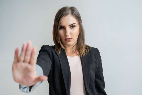 A serious businesswoman makes a stop gesture with her hand