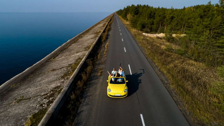 Друзья на ярком кабриолете на шоссе вдоль моря