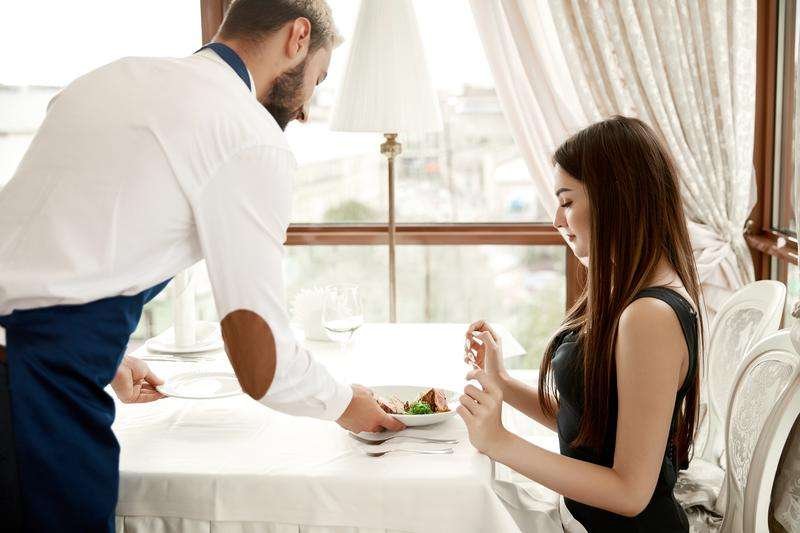A waiter serves a young lady in a restaurant