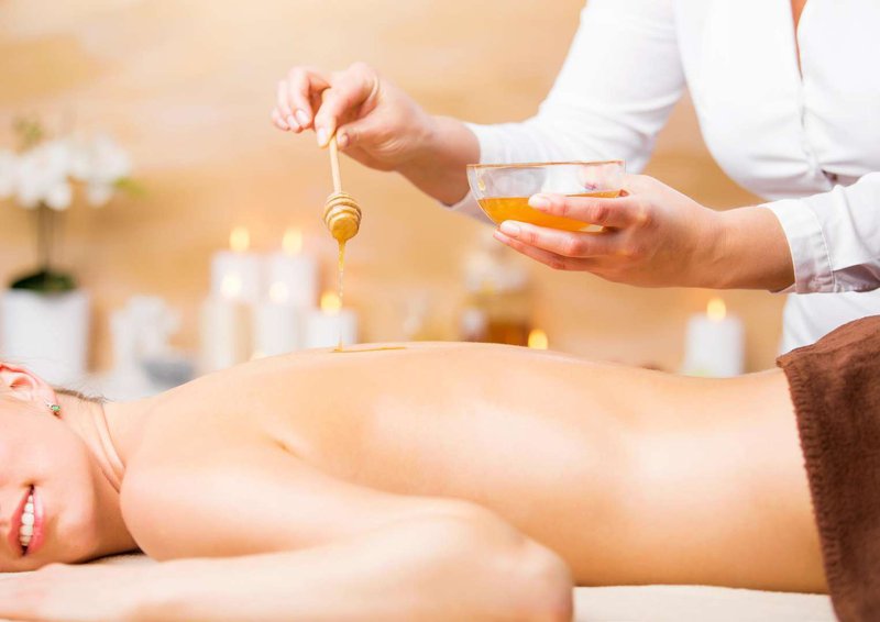 A woman on a massage session using honey