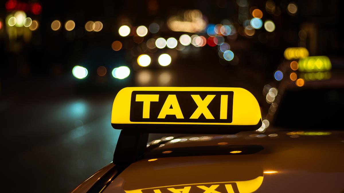 Желто-черный знак такси на крыше автомобиля ночью