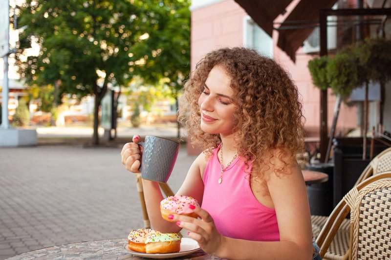 Молодая девушка наслаждается сладостями снаружи кафе